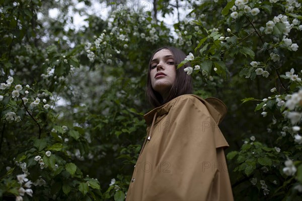 Low angle view of young woman by blossoms