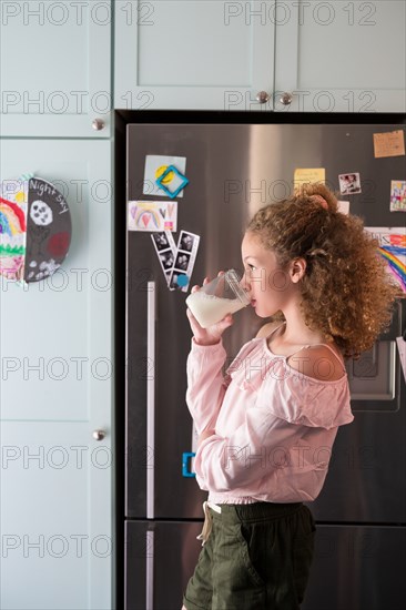 Girl drinking glass of milk in kitchen