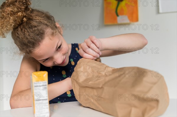 Girl looking into brown paper bag