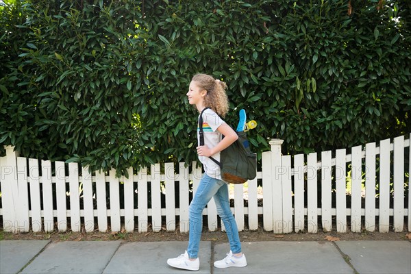 Girl with skateboard in backpack