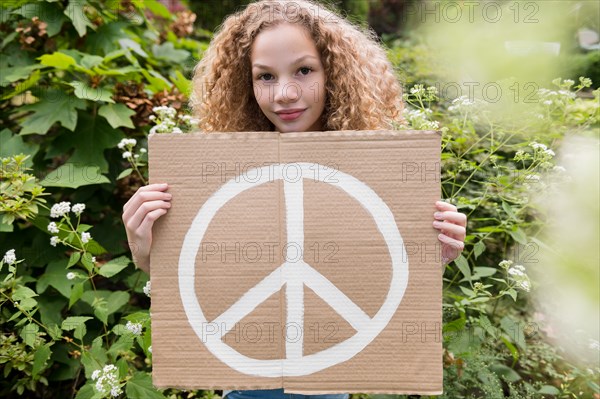 Girl holding sign with peace symbol