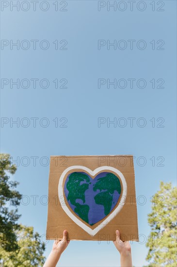 Young environmental activist holding sign against blue sky