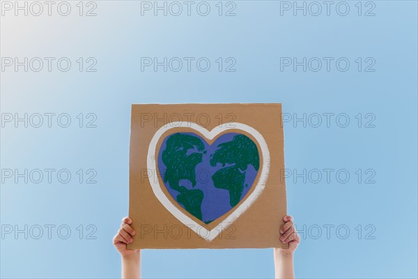 Young environmental activist holding sign against blue sky