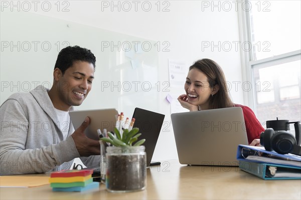 Coworker showing colleague tablet in office