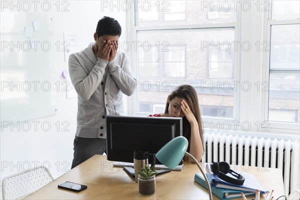 Stressed coworkers at computer together