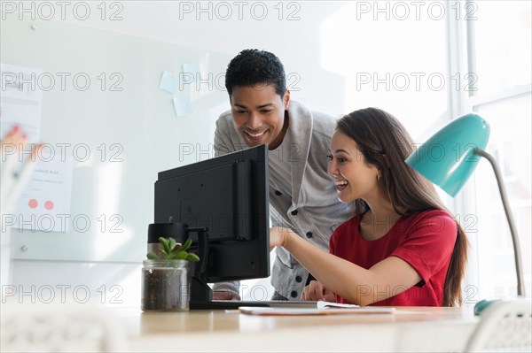 Coworkers smiling at computer together