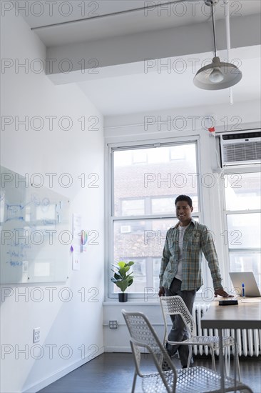 Businessman leaning on desk by whiteboard