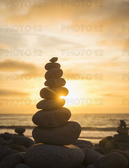 Stacked stones on beach at sunset