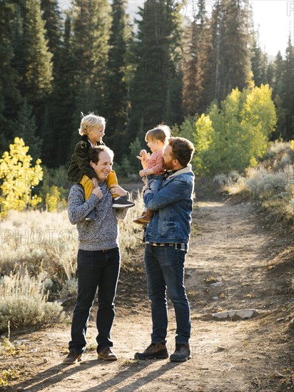 Two fathers piggybacking daughters while hiking