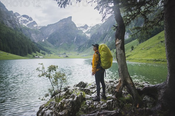 Woman wearing yellow backpack by Seealpsee lake in Appenzell Alps, Switzerland