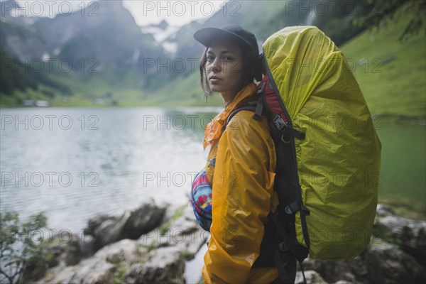 Woman wearing yellow backpack by Seealpsee lake in Appenzell Alps, Switzerland