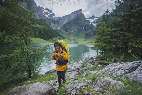 Woman wearing yellow hiking by Seealpsee lake in Appenzell Alps, Switzerland