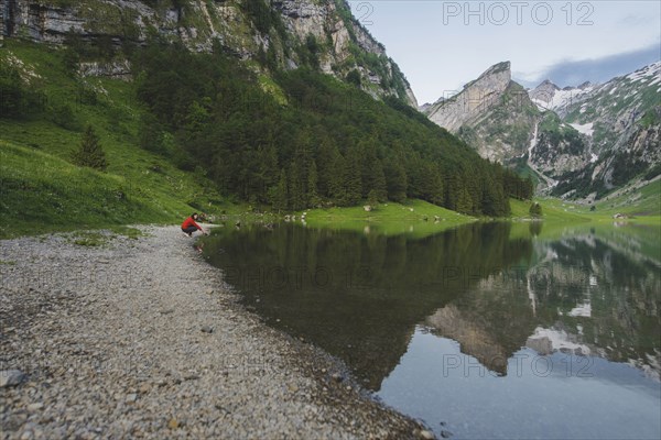 Woman crouching by Seealpsee lake in Appenzell Alps, Switzerland