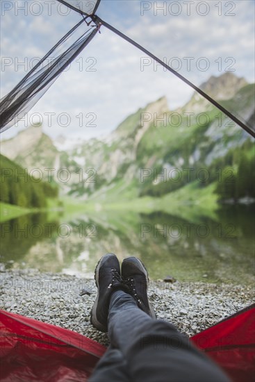 Woman's feet sticking out of tent by Seealpsee lake in Appenzell Alps, Switzerland