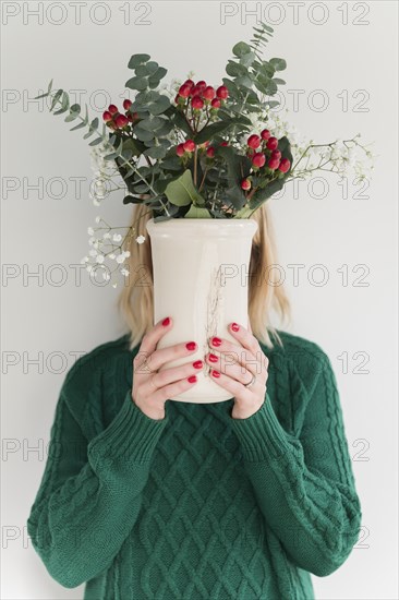 Woman wearing green holding vase of flowers