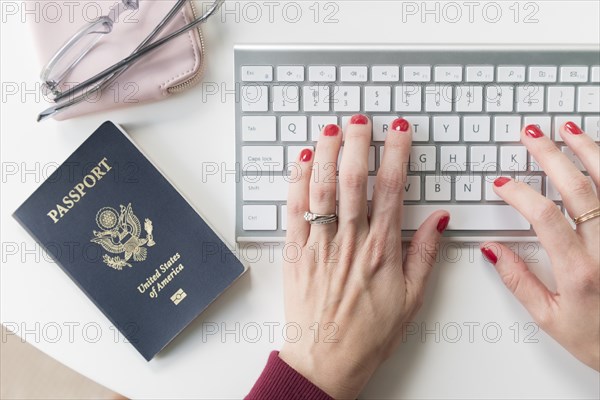 Woman typing on keyboard by passport