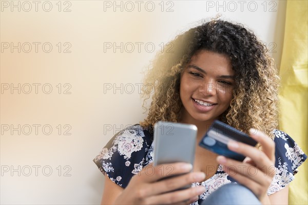 Smiling woman holding smart phone and credit card