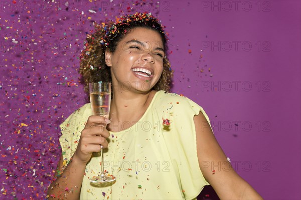 Smiling woman holding champagne glass under confetti