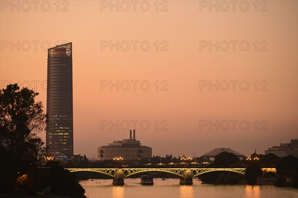 Triana Bridge in front of Sevilla Tower at sunset in Seville, Spain