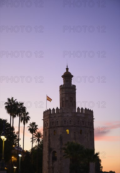 Torre del Oro by palm trees at sunset in Seville, Spain