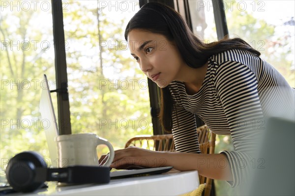 Woman leaning over table using laptop