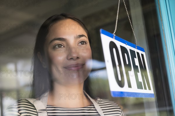 Smiling woman behind shop open sign