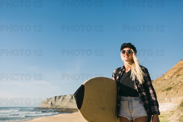 Smiling woman holding surfboard on beach