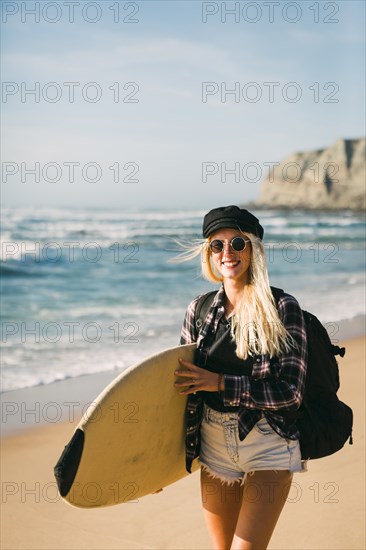 Smiling woman holding surfboard on beach