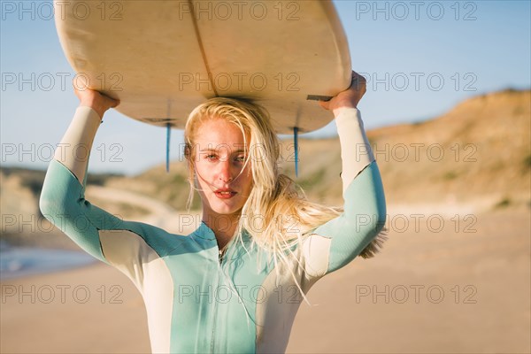 Woman holding surfboard above her head at beach