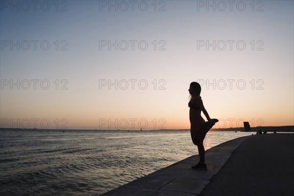 Silhouette of woman stretching at sunset