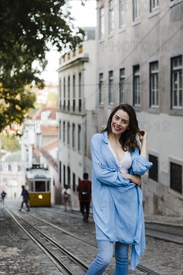 Smiling woman wearing blue coat by tram