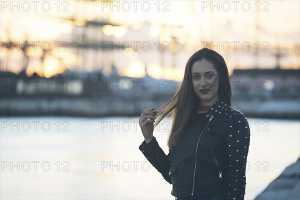 Woman wearing leather jacket by harbor