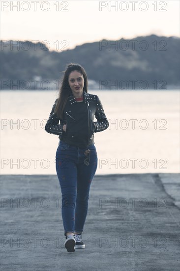 Woman walking on footpath by sea in Lisbon, Portugal