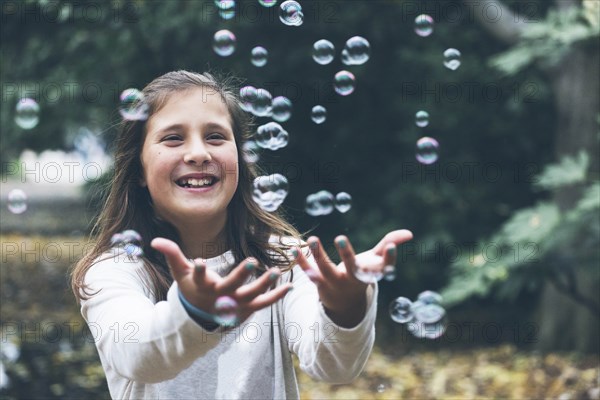 Smiling girl playing with bubbles