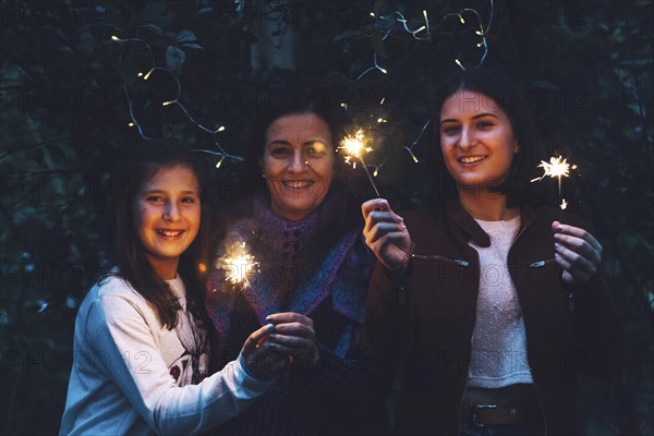 Mother and daughters smiling and holding sparklers