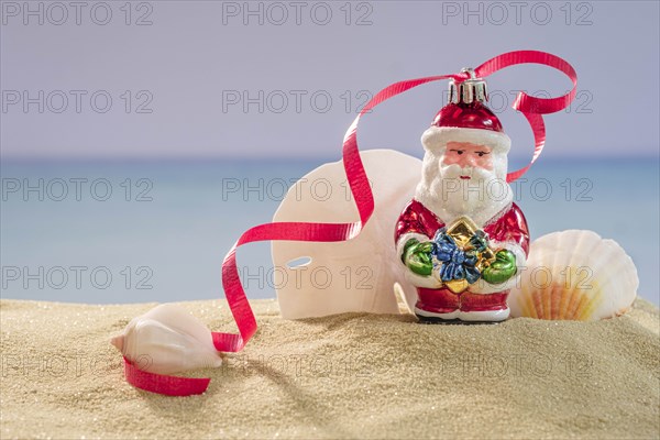 Santa decoration and shells on sand
