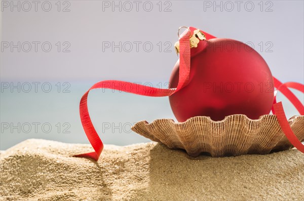 Red bauble on shell on sand