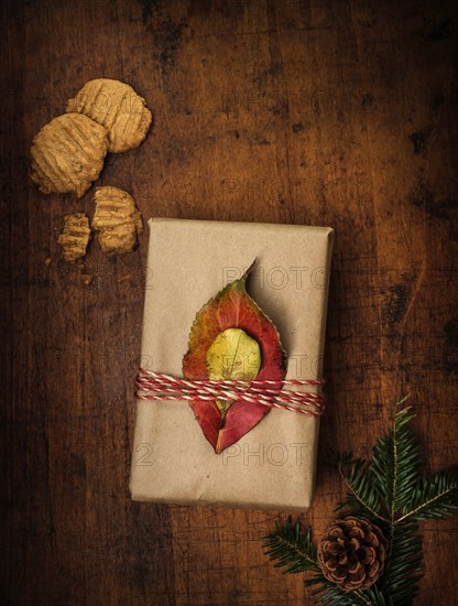 Leaves tied to Christmas present next to cookies