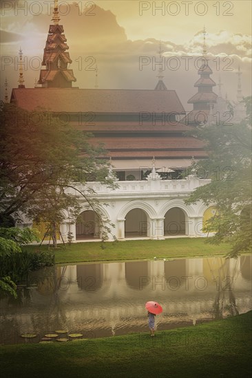 Woman holding umbrella by temple in Chiang Mai, Thailand