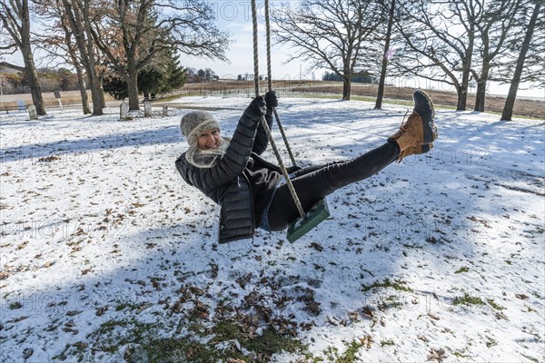 Smiling woman on swing in snow