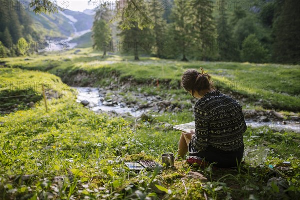 Woman painting with watercolors by river in Appenzell, Switzerland