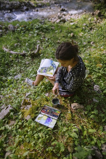 Woman painting with watercolors by river in Appenzell, Switzerland