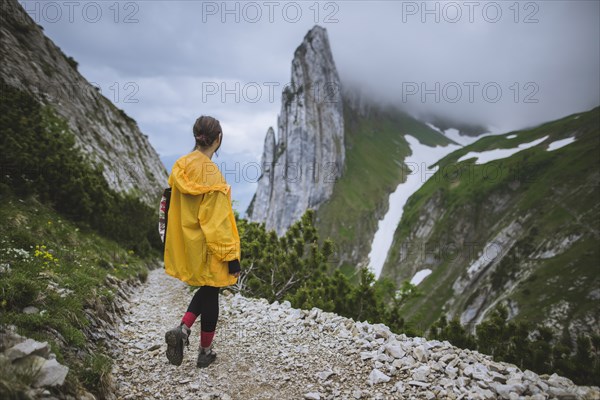 Woman wearing yellow jacket by mountains in Appenzell, Switzerland
