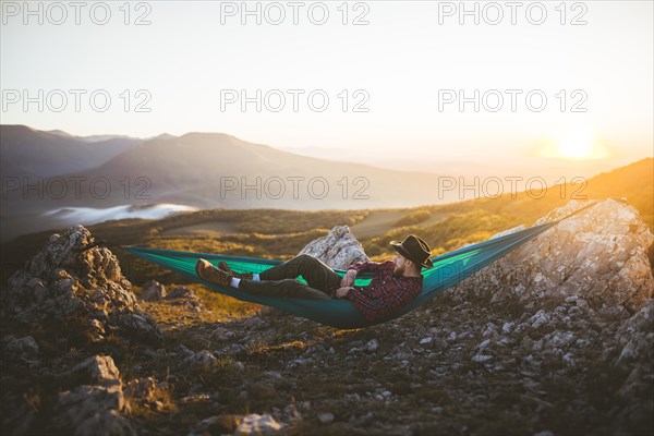 Man lying on hammock in mountain range