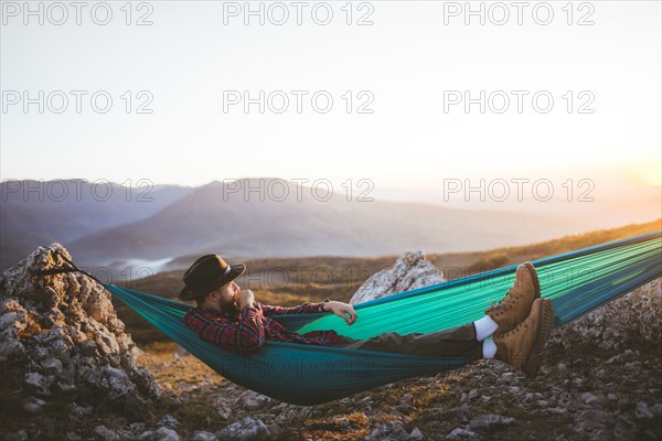 Man lying on hammock in mountain range