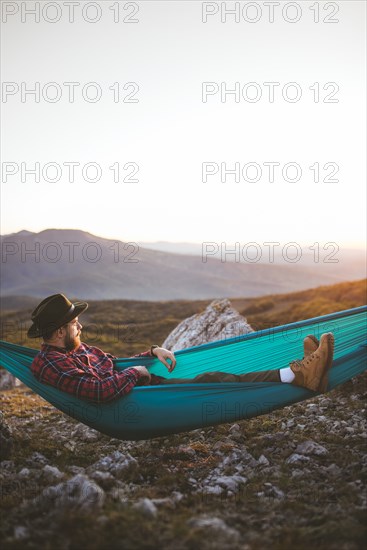 Man lying on hammock in mountain range