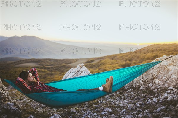 Man lying on hammock in mountain range