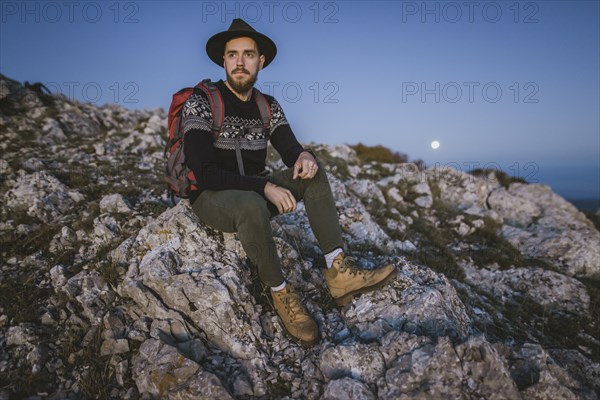 Man sitting on rock at sunset