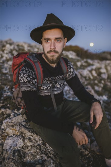 Man sitting on rock at sunset