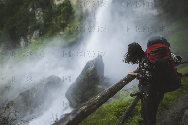 Woman wearing backpack by waterfall